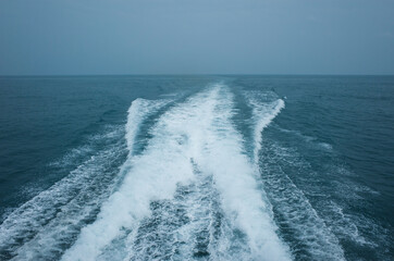 Trail on water surface behind high speed catamaran in Gulf of Thailand in grey weather