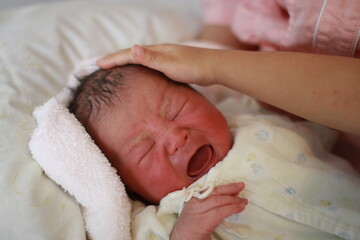 newborn baby crying in bed