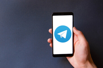 A male hand holds a smartphone, points a finger, types. Communication on a smartphone, correspondence. Place for text. Smartphone in hand on a gray  background.