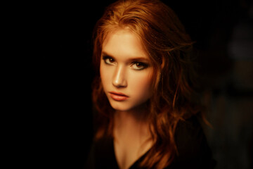 Fototapeta premium Black beauty close up portrait of red-haired redheaded woman with gorgeous beauty against black background in dramatic style. Classic woman portrait.