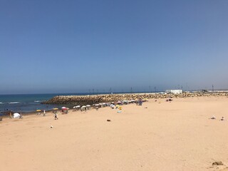 Fototapeta na wymiar ASILAH / MOROCCO - August 04 2019 : People on a beach in Asilah, Morocco. Asilah is a fortified town on the northwest tip of the Atlantic coast of Morocco. 