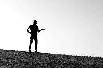 man silhouette with outstretched hand on low horizon with blurred background in black and white photo