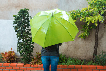 Rear view of a sad and lonely woman standing with an outdoor umbrella