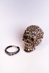 Vertical shot of a decorative skull made of smaller skulls and a leather ring on a white background