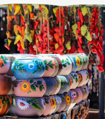 Fototapeta na wymiar Merchant wares with colorful clay pottery with bright ceramic chilli peppers in background