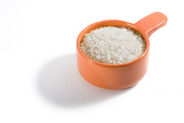 A portion of raw rice in a clay bowl on a white background