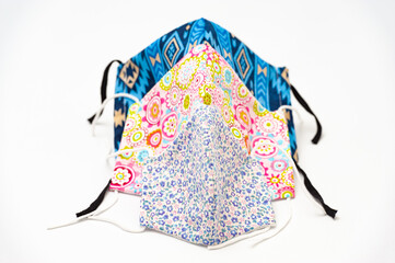 Colorful and floral (DIY) homemade fabric facial masks for protection against coronavirus (COVID-19) and other infectious diseases. Isolated on white background. 