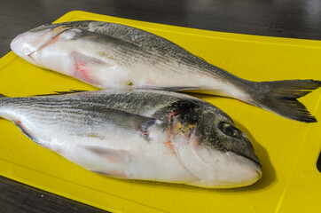 Two raw dorado fish on a cutting board