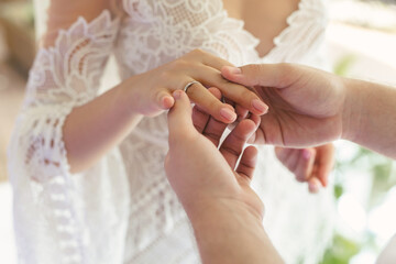 The groom puts the ring on the bride's finger in close-up