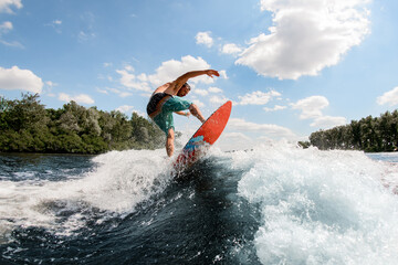 Active guy jumping on the waves of the river