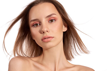 Sensual pretty woman with beautiful short brown hairs on wind, posing isolated on white. Close portrait of a girl with natural makeup.