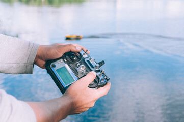 Man controls a remote control, a boat to bait fish in the lake.