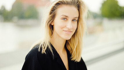 Young woman posing in a city smiling to a camera.