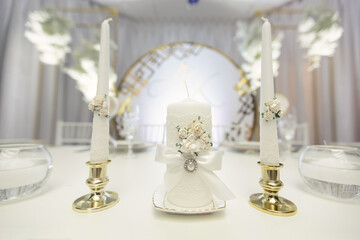 Wedding decor in white style with crystals, lace and flowers. Wedding candles for the family hearth
