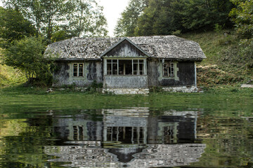 Fototapeta na wymiar Haunted House. The dilapidated house on the waterfront. Abandoned house. Water reflection. Lake. Swamp