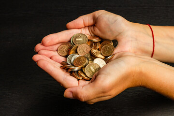 girl holding a handful of coins in her hands on a black table background