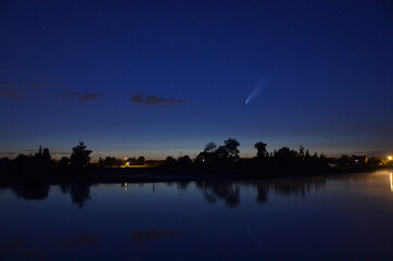 Kometa C.2020 F3 NEOWISE na wieczornym niebie z odbiciem w wodzie na jeziorze. - 365670293