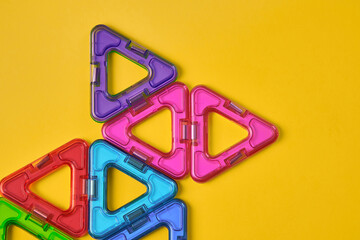 Top view of colorful magnetic building blocks on yellow background