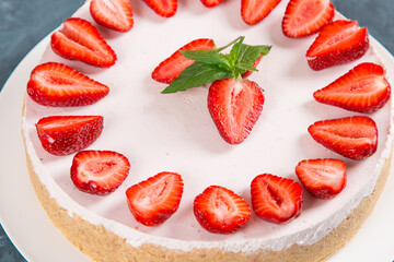 Sweet breakfast, delicious cheesecake with fresh strawberries and mint, homemade recipe without baking, on a dark blue stone table. Copy space.