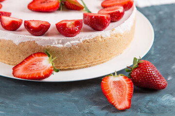 Sweet breakfast, delicious cheesecake with fresh strawberries and mint, homemade recipe without baking, on a dark blue stone table. Copy space.