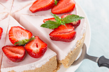 Sweet breakfast, delicious cheesecake with fresh strawberries and mint, homemade recipe without baking, on a blue stone table. Copy space.