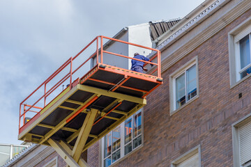 worker repairs the facade of a residential building on a basket of an industrial lift