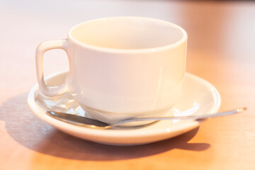white mock up cup and saucer with spoon on wooden table close up