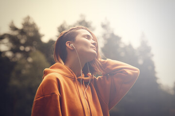 Hipster attractive girl in park using earphones