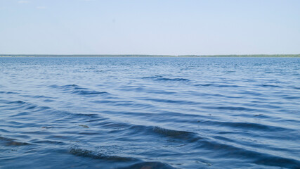 Light waves on the lake are illuminated by the evening rays of the sun. Blooming lake. Windy on a salt lake in Russia. Blue sky without clouds. Hot summer evening.