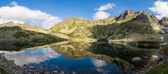 Scenic view of mountains clouds and green with a reflection in a frogs lake. Stony shore. zabie pleso. frogs lake. High Tatras, Slovakia Concept of nature and tourism