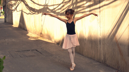 Little ballerina girl dancing along the street