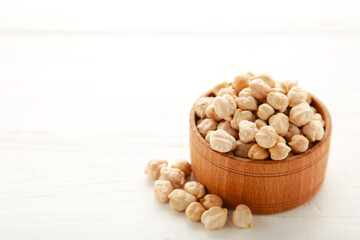 Uncooked dried chickpeas in wooden bowl on white background. Vegan food concept