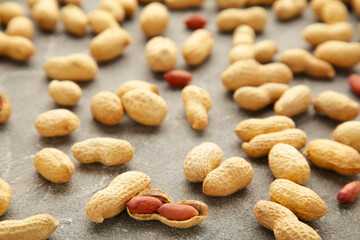 Fototapeta na wymiar Many peanuts in shells on grey background. Food texture