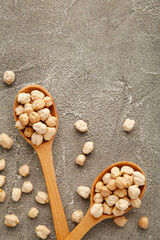 Uncooked chickpeas in wooden spoons on grey background