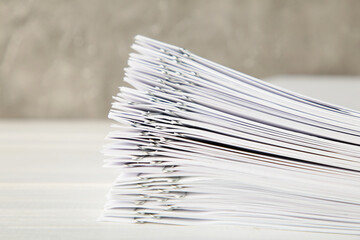 Stack of white paper with clips on grey background