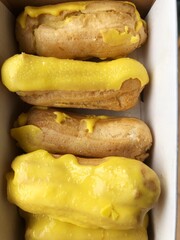 Delicious eclairs with yellow glaze in a box