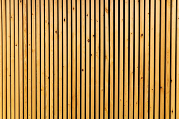 Vertical thin wooden slats on wall in modern interior. Natural brown color - obrazy, fototapety, plakaty