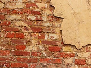 Weathered brick wall fragment.Empty old Brick wall texture.Painted distressed wall surface.Grungy wide brickwall.Shabby building facade with demaged plaster.Grungy red stonewall background.Copy space.