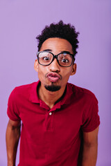 Cute bearded guy posing with kissing face expression. Indoor shot of funny black man in red outfit expressing love.