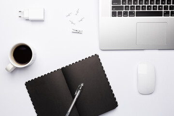 Work place at quarantine time, empty dark notebook with cup of coffee on white table.