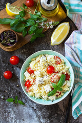 Oriental cuisine. Healthy salad with couscous, tomatoes, feta cheese, basil, chili pepper and olive oil. Top view flat lay background.