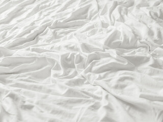 Background with white crumpled bed sheet. Creased soft linen with copy space. Unmade bed in bedroom of cozy home.