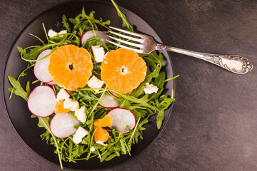 Diet Mediterranean salad with chopped tangerines, radishes, arugula lettuce and pieces of sheep cheese