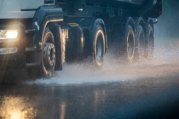 Rain water splash flow from wheels of heavy truck moving fast in daylight city with selective focus. © lucky pics