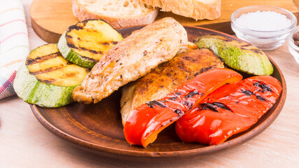 Diet American homemade dish - fried chicken breast with grilled vegetables, bell pepper and young zucchini in a plate, close-up