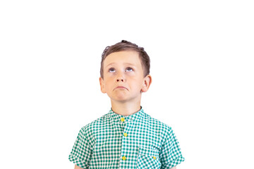 A sad boy with a crooked mouth in a green shirt looks up somewhere. A beautiful child with a sad...