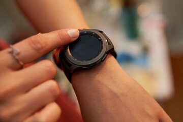 Top view of female hands setting smart watch. Close up of woman hands using smartwatch. Dramatic ambient light, golden hour.