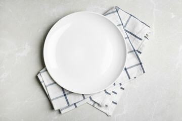 Empty white plate and napkin on light grey marble table, flat lay