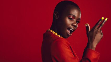 Stylish woman with finger gun on red background