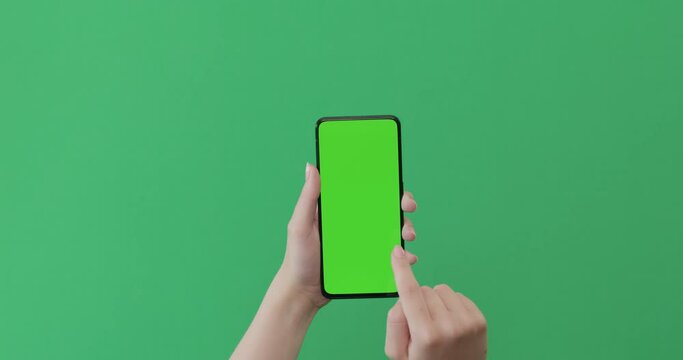 Young woman hand use smartphone with green screen on green background